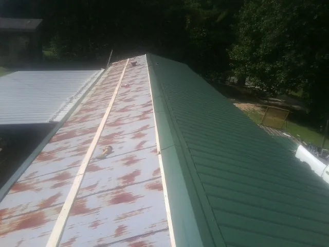 Old rusted panels beside newly installed green metal roofing — Wind Damage Roof Repair by Roofing Brothers in New Port Richey