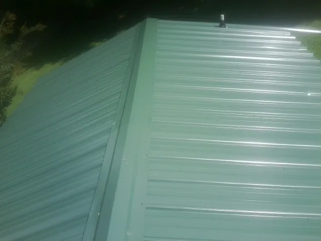 New green metal panels meeting at the ridge of a roof — Flat Roof Repair work by our crew in New Port Richey