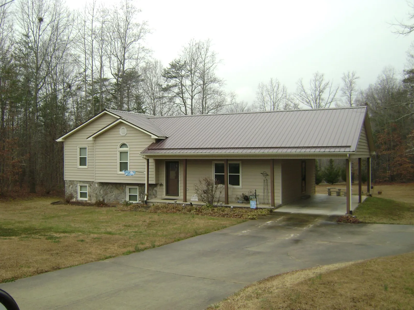 Brown metal roof on a tan split level home with an attached carport in New Port Richey