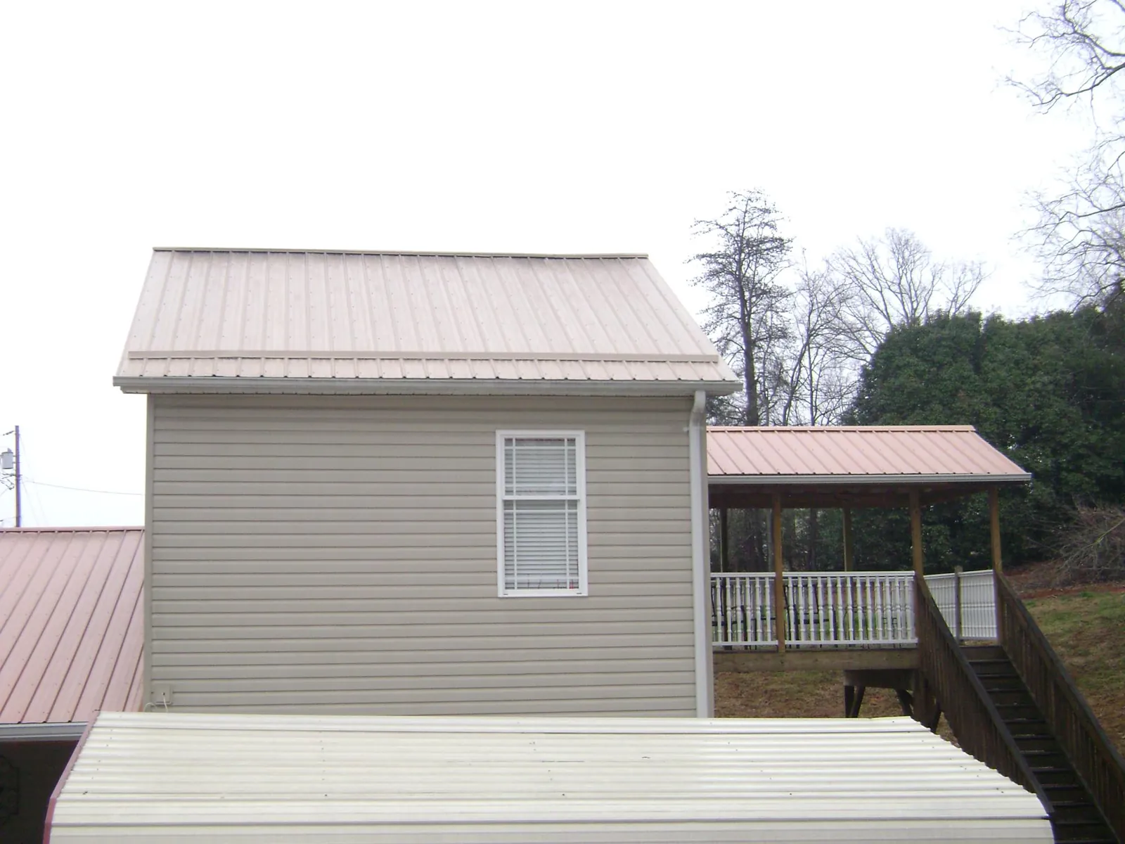 Tan metal roofs on a two story addition and attached porch, from a Roof Replacement job in New Port Richey