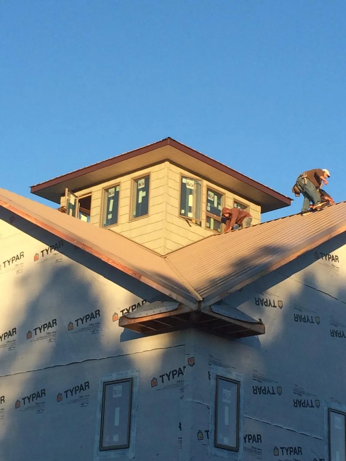 Roofers working around a rooftop cupola on a new metal roof at sunset — Roof Waterproofing in New Port Richey by Roofing Brothers